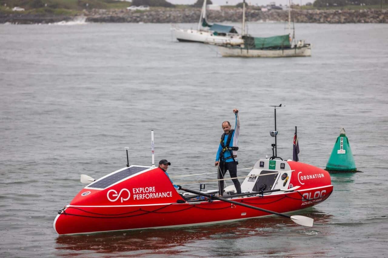 Grant 'Axe' Rawlinson raising his arm in celebration aboard the Explore Performance ocean rowing boat on arrival in Australia